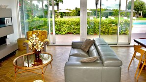 A modern living room with a grey leather sofa, a glass coffee table, and a yellow armchair.
