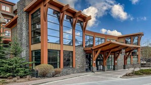 A modern building with large windows, a stone facade, and a wooden entrance canopy.