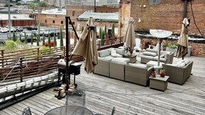A rooftop patio with outdoor seating, a metal table, and umbrellas. - Upscale Downtown Luxury Penthouse with PARKING (Macon)