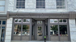 A building with a stone facade, large windows, and a visible entrance with a door. - Upscale Downtown Luxury Penthouse with PARKING (Macon)