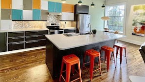 A modern kitchen with a large island, wooden flooring, and colorful cabinets. - Upscale Downtown Luxury Penthouse with PARKING (Macon)