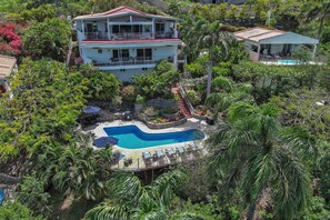 A multi-story building with a swimming pool surrounded by lush greenery.