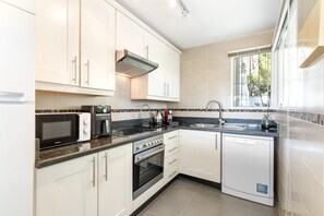 A modern kitchen with white cabinets, a built-in microwave, a stove, and a dishwasher.