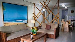 A living room with a sofa, a coffee table, and a dining area with chairs and a table. - Suites del Sol (Mérida)