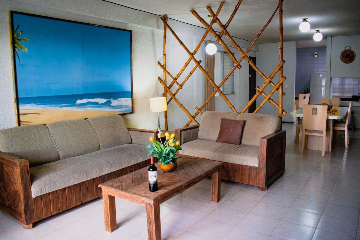 A living room with a sofa, a coffee table, and a dining area with chairs and a table.
