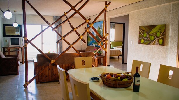A dining area with a table set for two, a basket of fruit, and a bottle of wine. - Suites del Sol (Mérida)