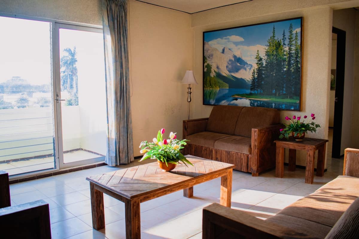 A living room with a sofa, coffee table, and a painting of a mountain landscape.
