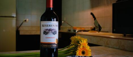 Una botella de vino Reserva Carmenere, un plato de arándanos y girasoles sobre una encimera de cocina.