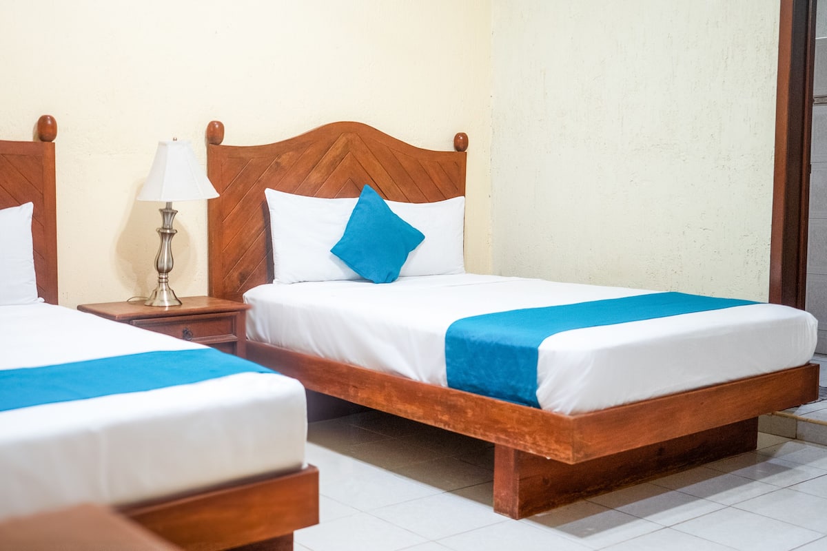 Two single beds with wooden headboards, white bedding, and blue accents.
