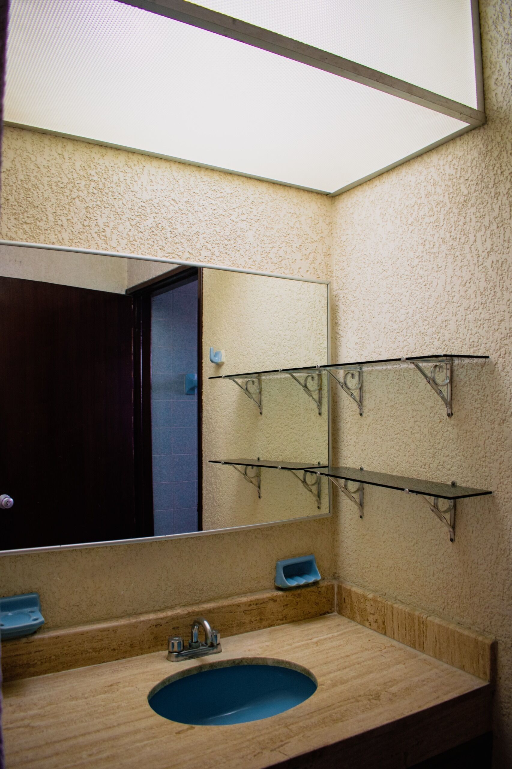 Une salle de bain avec un lavabo en bois, un miroir et deux étagères au-dessus du lavabo.