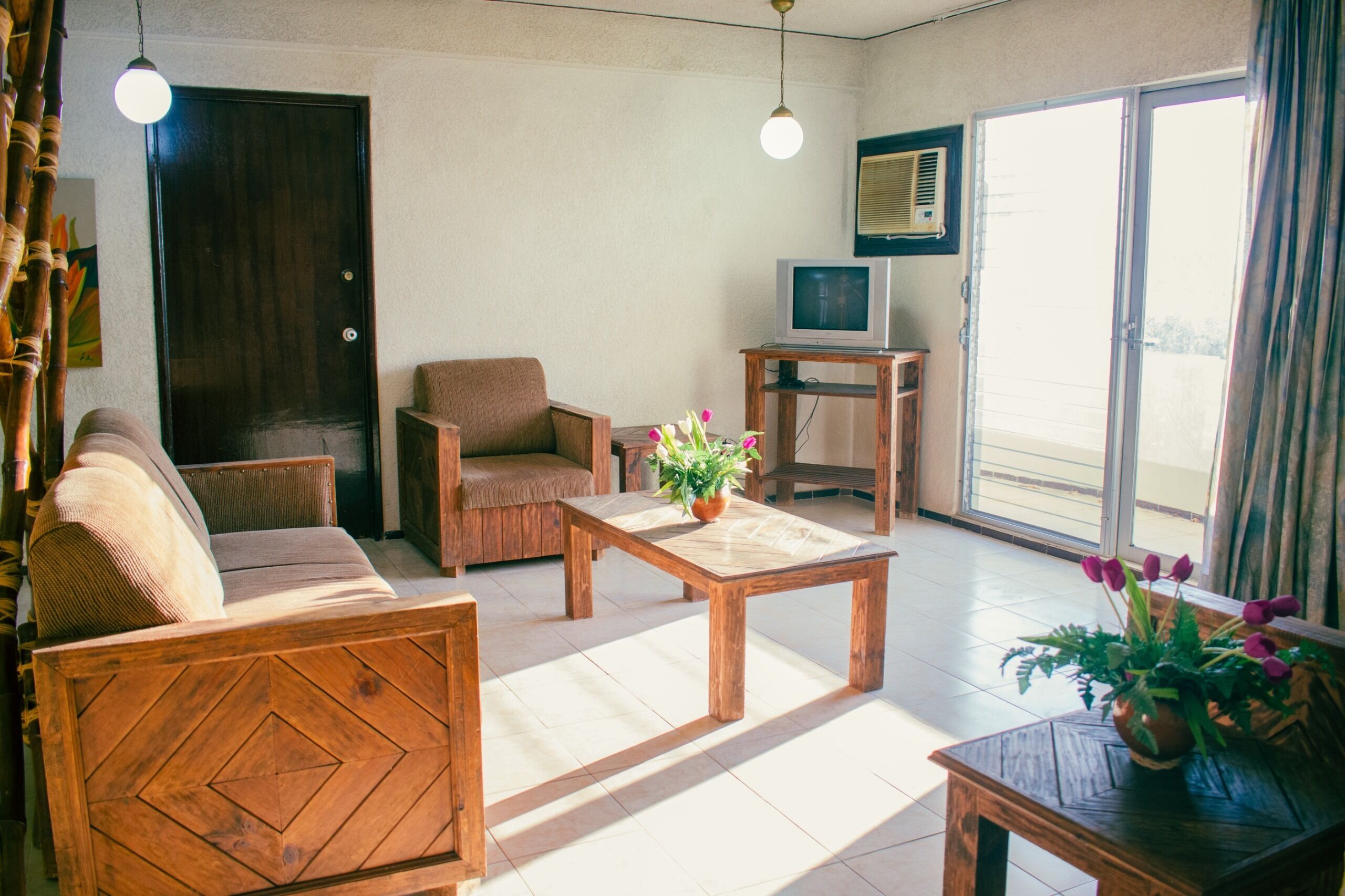 A living room with a sofa, armchair, coffee table, and a TV on a stand.