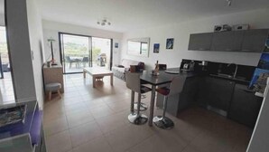A modern kitchen with a dining area, a small seating space, and a view to the outside. - Grand T2, Centre Porticcio, 'tout à Pied', vue mer (Grosseto-Prugna)