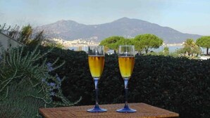 Two glasses of a yellow beverage on a wooden table with a scenic mountain view in the background. - Grand T2, Centre Porticcio, 'tout à Pied', vue mer (Grosseto-Prugna)