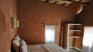 Ein rustikales Schlafzimmer mit einem hölzernen Bett, einem gewebten Wandbehang und einer schlichten Holzablage.