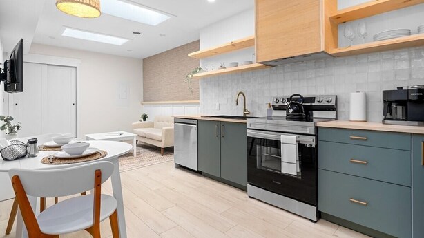 Una cocina moderna con comedor, que incluye un horno empotrado, una cafetera y estantes de madera sobre la encimera.