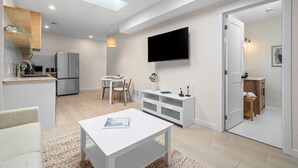 Un espacio habitable moderno con cocina, comedor y televisor montado en la pared.