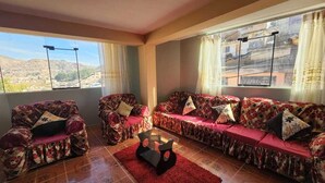 A living room with two patterned sofas, a glass coffee table, and a red rug.