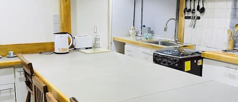 Een microgolfoven, een oven, een kookplaat, kookgerei, borden en bestek