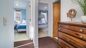 Un pasillo que conduce a un dormitorio con una cama, un aparador y un objeto decorativo sobre él.
