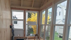Un interior de madera con una mesa y sillas, ventanas amplias y vistas al exterior.