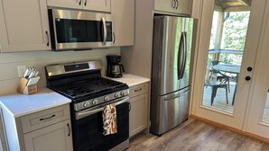 A modern kitchen with stainless steel appliances, a gas stove, and a refrigerator. - Luxury cabin in county but not far from downtown. Hot tub on back porch.  (Ellijay)