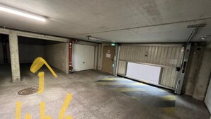 Eine Parkgarage mit Betonböden, Metall-Garagentoren und einem gelben Pfeil auf dem Boden.