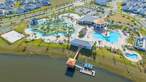 An aerial view of a resort with multiple swimming pools, a water slide, and a dock extending into a lake. - Magical Townhome private pool in Storey Lake (Kissimmee)
