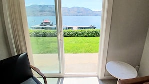 Une pièce dotée d’une grande porte-fenêtre coulissante donnant sur un balcon avec vue sur un lac et des montagnes.