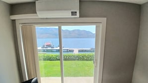 Une pièce dotée d’une porte-fenêtre coulissante donnant sur un balcon avec vue sur un lac et des montagnes.