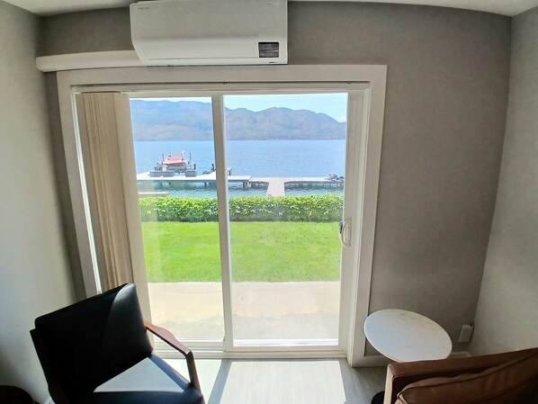 A room with a sliding glass door leading to a balcony with a view of a lake and mountains. - Seclusion Bay Resort 99. Honeymoon Escape Lux Lake. Stunning, Modern, Lake Views (West Kelowna)