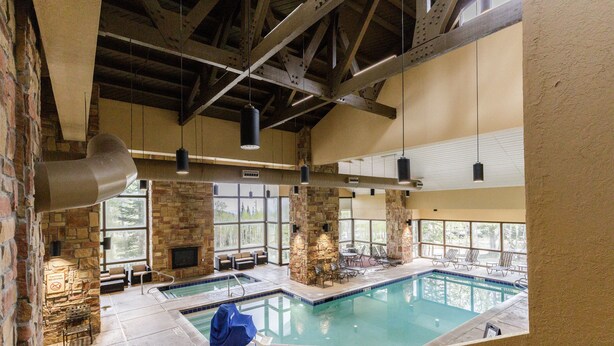 Una piscina interior con paredes de piedra, chimenea y zona de estar exterior.