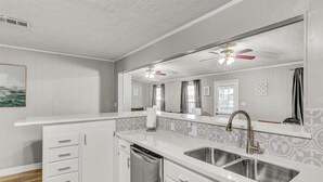 Una cocina moderna con armarios blancos, un lavamanos doble y un lavavajillas.