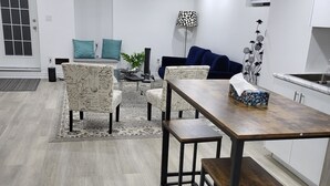 Moderni keittiö, jossa on ruokailutila. Tilaan kuuluu puinen pöytä ja tuolit, sohva sekä koristeellinen kasvi.