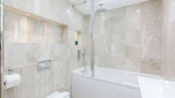 A modern bathroom with a glass-enclosed shower, a white bathtub, and a built-in toilet.