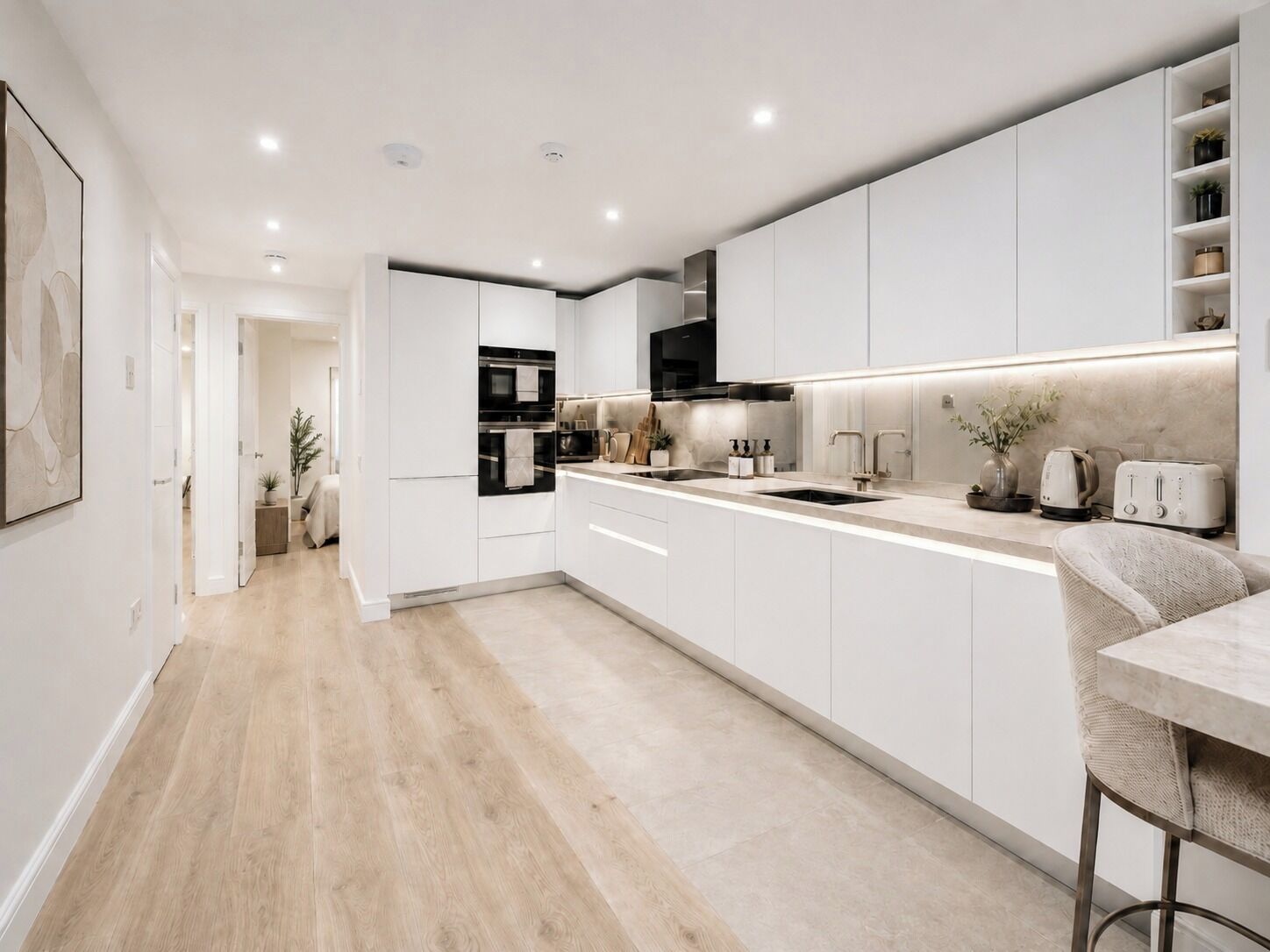 Une cuisine moderne avec des meubles blancs, un îlot central, un four encastré et un four à micro-ondes.