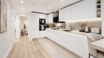 Een moderne keuken met witte kasten, een centraal eiland, een ingebouwde oven en een magnetron.