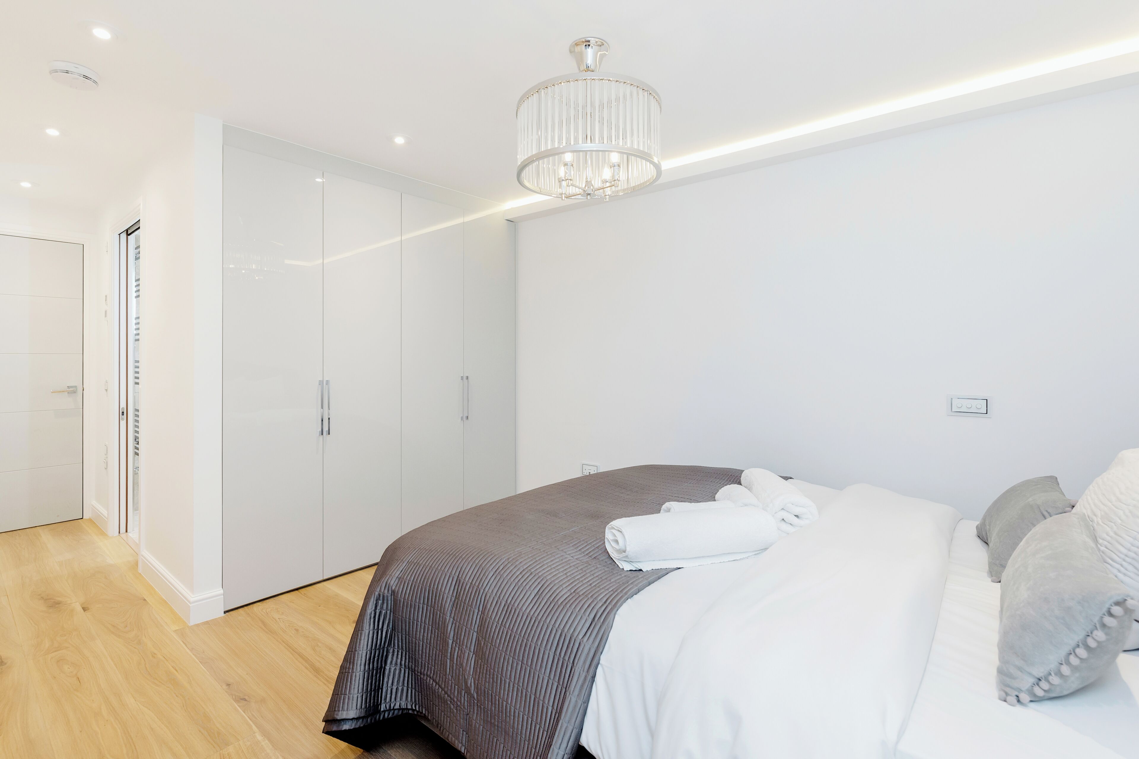 Une chambre moderne avec un grand lit, un lustre et un dressing.