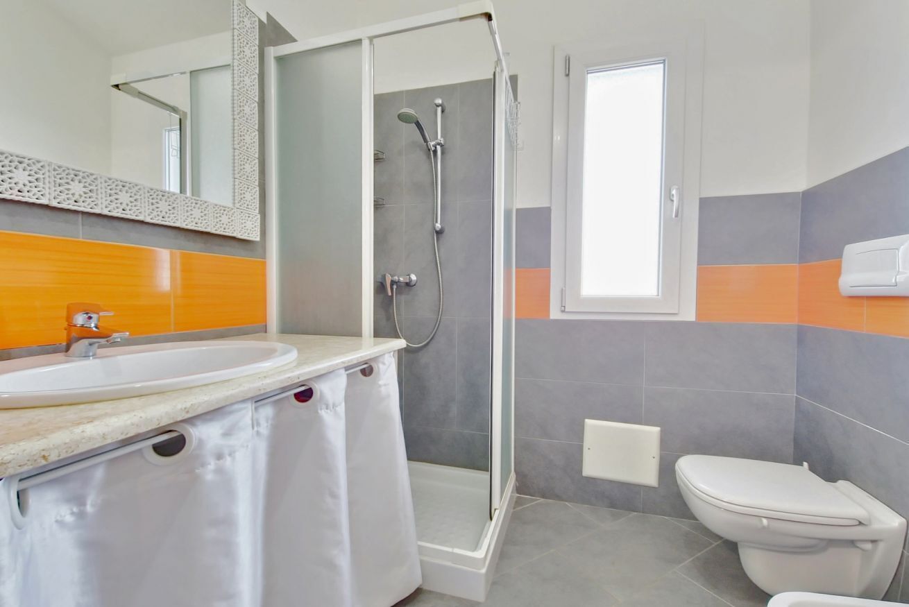 A bathroom with a shower, toilet, sink, and a mirror.