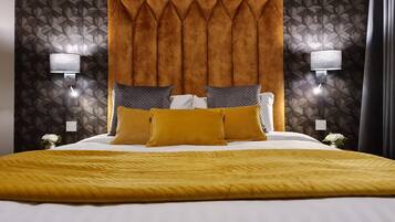 A hotel room with a large bed, a headboard with a geometric pattern, and two wall-mounted lamps.