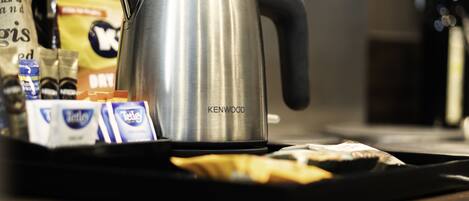 A stainless steel Kenwood coffee maker on a tray with various coffee pods and a packet of sugar.