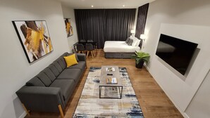 A modern living room with a grey sofa, a coffee table, a TV, and a large window with curtains.