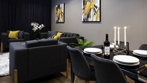 A modern dining area with a black dining table, white plates, and candles.