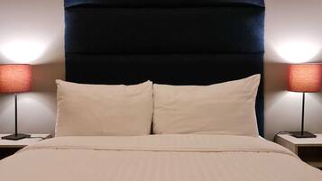 A hotel room with a large bed, two bedside lamps, and a dark headboard.
