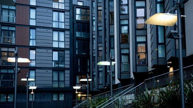 A modern building with multiple floors, large windows, and a staircase with metal railings.