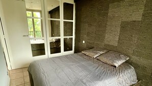 A bedroom with a bed, a wardrobe, and a view of greenery outside.