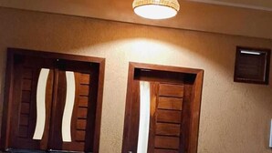 A building facade with two wooden doors and a single window, each with a curtain. - Pousada Essência de Atins (Barreirinhas)