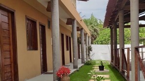 A covered outdoor area with a pathway, potted plants, and a building with columns and doors. - Pousada Essência de Atins (Barreirinhas)