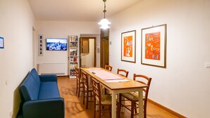 Un comedor con una larga mesa de madera, seis sillas, un sofá azul y una estantería.