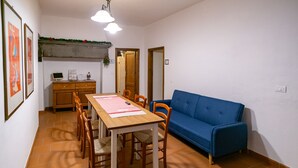 Un comedor con una mesa de madera, sillas, un sofá azul y piso de baldosas.