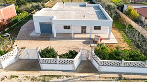 Une maison moderne à deux étages, dotée d’un toit plat, d’un garage et d’une allée pavée.